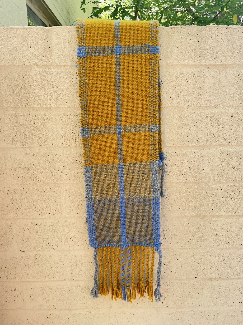 Mustard scarf hanging off a lightly coloured wall